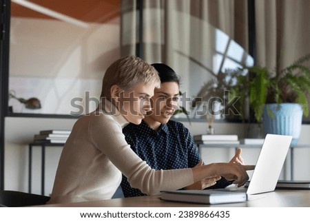Corporate teacher showing new employee learning video at laptop, company mentor training intern. Diverse coworkers watching presentation, reading message, working together at computer