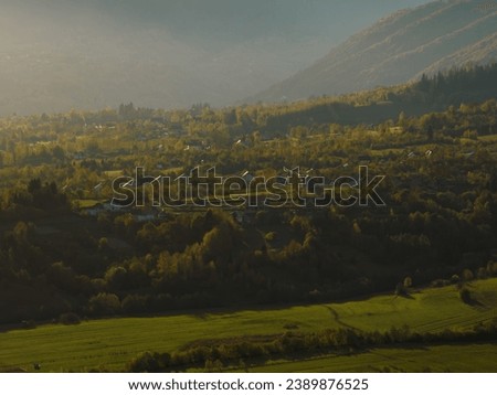 Aerial Footage of landscape morning ambiance at Village Zarnesti  with green field and Piatra Craiului mountain as background