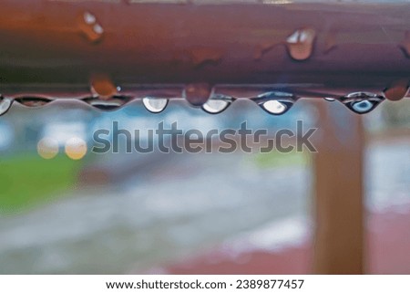 Raindrops on a metal pipe on an autumn day