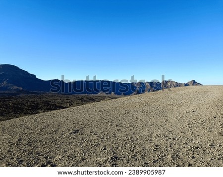 Surroundings of Teide. Volcano located on the Spanish island of Tenerife, you can see the inhospitable terrain, blue sky, large rocks of volcanic origin and typical vegetation. Royalty-Free Stock Photo #2389905987