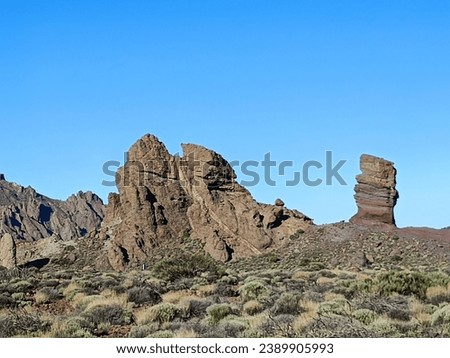Surroundings of Teide. Volcano located on the Spanish island of Tenerife, you can see the inhospitable terrain, blue sky, large rocks of volcanic origin and typical vegetation. Royalty-Free Stock Photo #2389905993