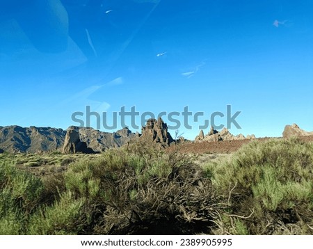 Surroundings of Teide. Volcano located on the Spanish island of Tenerife, you can see the inhospitable terrain, blue sky, large rocks of volcanic origin and typical vegetation. Royalty-Free Stock Photo #2389905995
