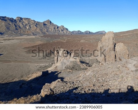 Surroundings of Teide. Volcano located on the Spanish island of Tenerife, you can see the inhospitable terrain, blue sky, large rocks of volcanic origin and typical vegetation. Royalty-Free Stock Photo #2389906005