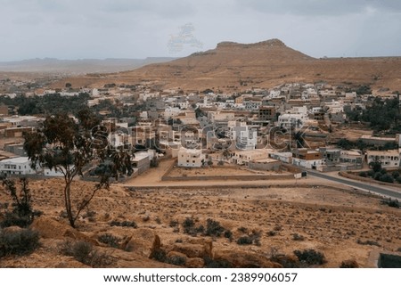 The panoramic view of Foum Tataouine, Dahar region of Tunisia, with Maghrib architecture, dusty hills, and desert around. Royalty-Free Stock Photo #2389906057