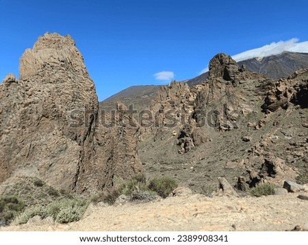 Surroundings of Teide. Volcano located on the Spanish island of Tenerife, you can see the inhospitable terrain, blue sky, large rocks of volcanic origin and typical vegetation. Royalty-Free Stock Photo #2389908341