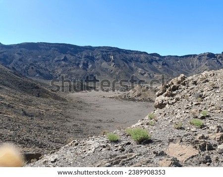 Surroundings of Teide. Volcano located on the Spanish island of Tenerife, you can see the inhospitable terrain, blue sky, large rocks of volcanic origin and typical vegetation. Royalty-Free Stock Photo #2389908353