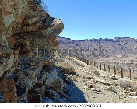 Surroundings of Teide. Volcano located on the Spanish island of Tenerife, you can see the inhospitable terrain, blue sky, large rocks of volcanic origin and typical vegetation. Royalty-Free Stock Photo #2389908361