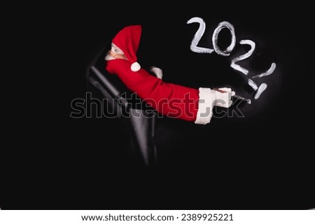 Santa Claus writes the numbers 20224 on a black paper with space for other text.