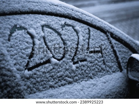 close-up snow on the car where the numbers are written 2024, textured snowy background Royalty-Free Stock Photo #2389925223