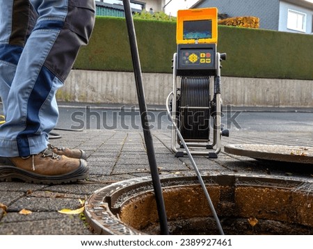 A drain cleaning company checks a blocked drain with a camera before flushing it out Royalty-Free Stock Photo #2389927461