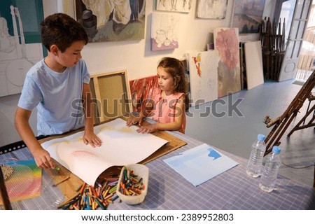 Adorable diverse children, a teenage boy and preschool girl drawing on white paper sheet during art class. People. Kids and hobbies.