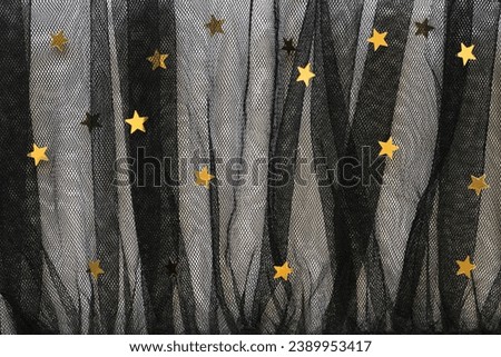 Rich chiffon texture tissue: elegant folded black mesh fabric tulle, holiday dress lace textile with yellow golden stars. Transparent festive new year cloth, luxurious birthday background