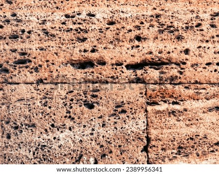 This is a close-up photo of a red-brown rock wall background. The rock has a porous texture and is in horizontal layers. This image is suitable as a graphic resource.