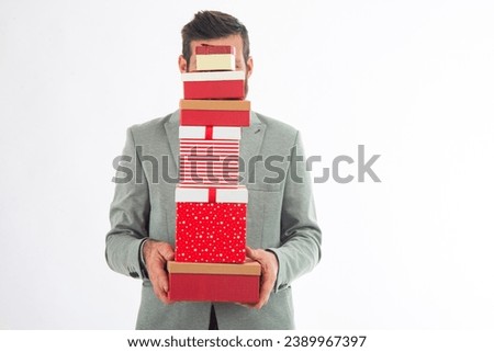 Man holding presents wrapped in gift paper  isolated on white background. Man returning home from shopping holding pile of christmas present boxes.