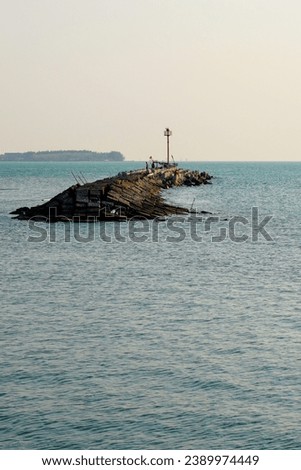 looks far away from a wide angle from the lighthouse at the breakwater in the middle of the sea.  Royalty-Free Stock Photo #2389974449