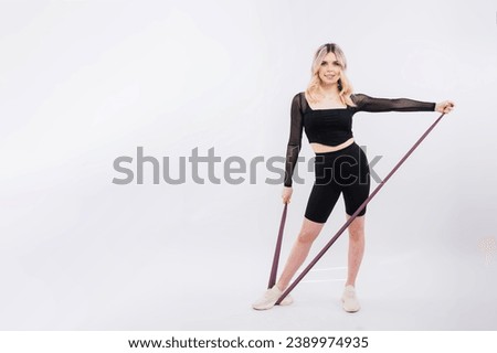 Young woman workout with resistance band on white background. Strength and motivation.