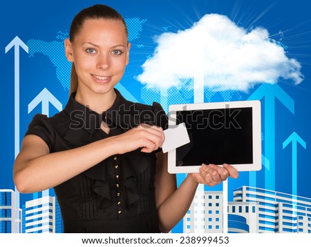 Beautiful businesswoman holding blank tablet PC and blank business card in front of PC screen. World map, buildings, clouds and vertical arrows as backdrop