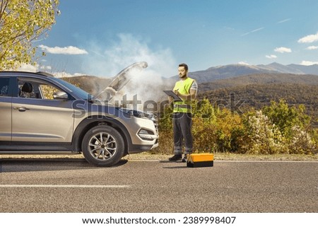 SUV on the road with an open hood and a road help worker writing a document 