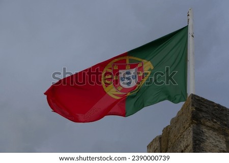 Beautiful large Portuguese flag waving in the wind against blue sky. Portuguese Flag Waving Against Blue Sky. Flag of Portugal waving, against blue sky
