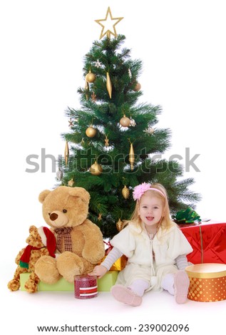 Little girl sitting under the Christmas tree.Studio photo, isolated on white background.