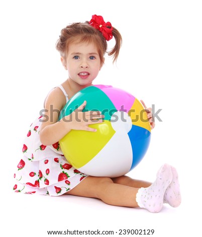 girl sitting on the floor and holding a ball. Studio photo, isolated on white background.