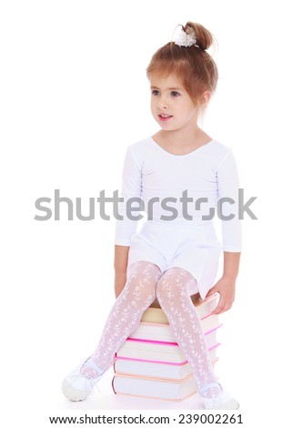 Adorable little girl is sitting on a big pile of books. Studio photo, isolated on white background.