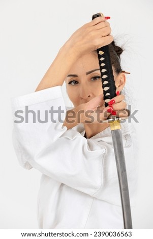 Aikido master woman in traditional samurai hakama kimono with black belt with sword, katana on white background. Healthy lifestyle and sports concept. Royalty-Free Stock Photo #2390036563