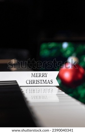 Merry Christmas note on the piano with Christmas ornaments in background