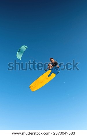 Kitesurfing, professional rider flying performing a trick, looking at the camera while hovering in the air Royalty-Free Stock Photo #2390049583