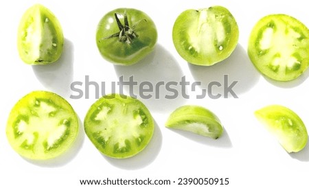 Freshly picked green tomatoes cut into various shapes on a simple white background. Royalty-Free Stock Photo #2390050915