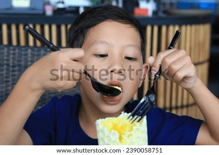 adorable Asian little boy kid eating Golden Honeycomb mousse cake in the cafe.