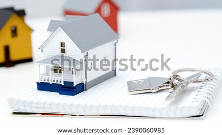 a model of a house with house keys on the table. High quality photo