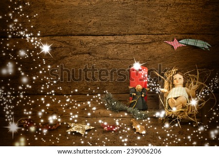 Christmas card with space for message, the Child Jesus in his crib on old wooden background and Christmas decorations