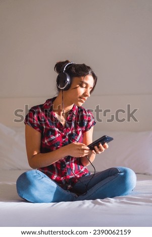 Vertical photo of a cute woman listening to music alone in the bed