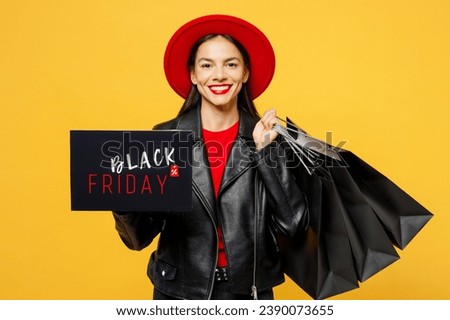 Young smiling fun woman wearing casual clothes red hat hold shopping paper package bags card sign with Black Friday written text inscription isolated on plain yellow background. Sale buy day concept