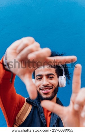 Vertical photo with copy space of a young hispanic man framing with the hands while listening to music