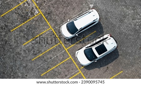 Aerial view of outdoor vehicle parking area in urban areas with paving blocks and yellow lines for dividing signs between parked vehicles. Cars parking lot during the day with 90 degree angle.