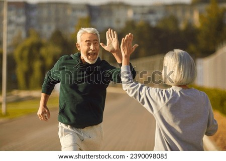 Good job. Well done. Two happy old people finish jogging and have fun. Cheerful excited male athlete in sportswear high fives female partner after outdoor spring summer running workout. Sport concept Royalty-Free Stock Photo #2390098085