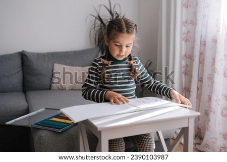Five year old girl drawing at home. Adorable little girl with beautiful hairstyle painting 