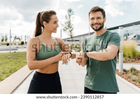 Uses a fitness watch and an app for running sports, a slim woman and a sporty man in sportswear. Motivation for fitness training three times a week. Sports person fitness trainer. Royalty-Free Stock Photo #2390112857