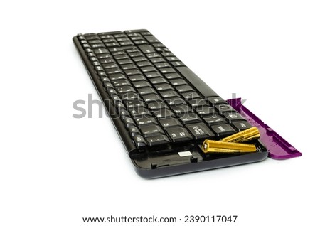 Black wireless keyboard with purple cover and two batteries. Background white