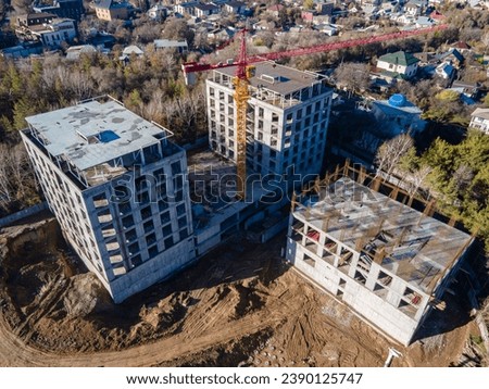 An aerial view of the construction of a residential building. The footage shows the activity of construction workers and heavy machinery. The boom of a large tower crane, metal structures and concrete