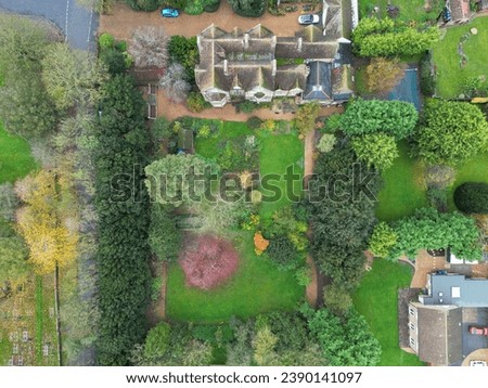 Drone top down view of a very old English mansion seen within lush grounds in late autumn.