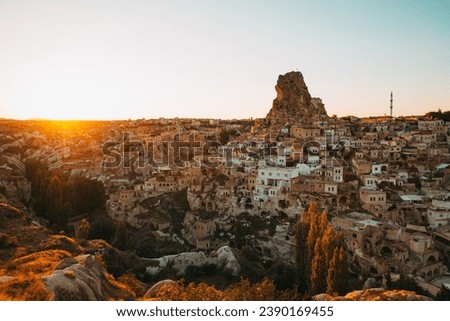 The sun's last rays illuminate the unique landscape of Cappadocia, casting a golden glow over the town's ancient, rock-hewn dwellings and the formidable fortress that has stood watch for centuries.