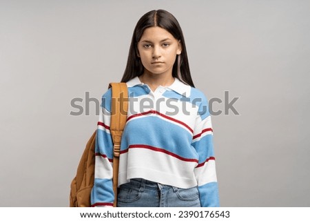 Focused teen student girl with backpack on shoulder isolated studio background. Serious unsmiling joyless young teenager schoolgirl looking at camera. Beginning of academic year, admission to college Royalty-Free Stock Photo #2390176543