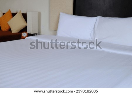 Perspective view of white clean arranged bed, king size, with pillows