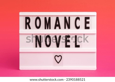 The word romance novel on lightbox isolated pink background. Love book romance library concept. Literary Genres.