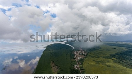 Rainclouds loom over a tranquil Amazonian village. Royalty-Free Stock Photo #2390208373