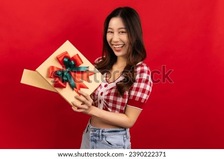 Happy smiling asian woman holding gift box over red background.