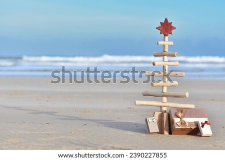 Wooden Christmas tree with gift boxes on the beach with copy space. Summer Christmas in the southern hemisphere  Royalty-Free Stock Photo #2390227855